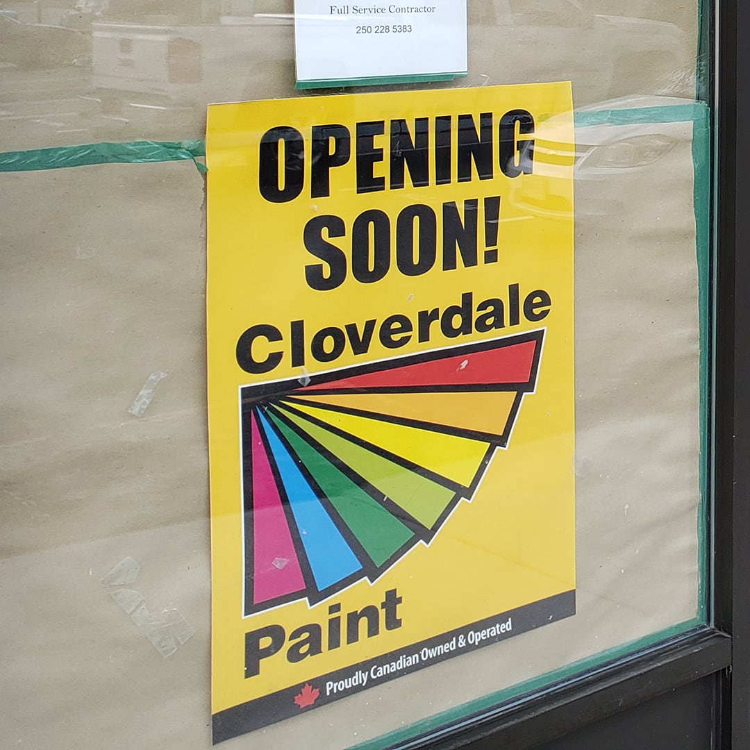 Yellow sign on a papered-up window of a commercial business, with the text stating Opening Soon!