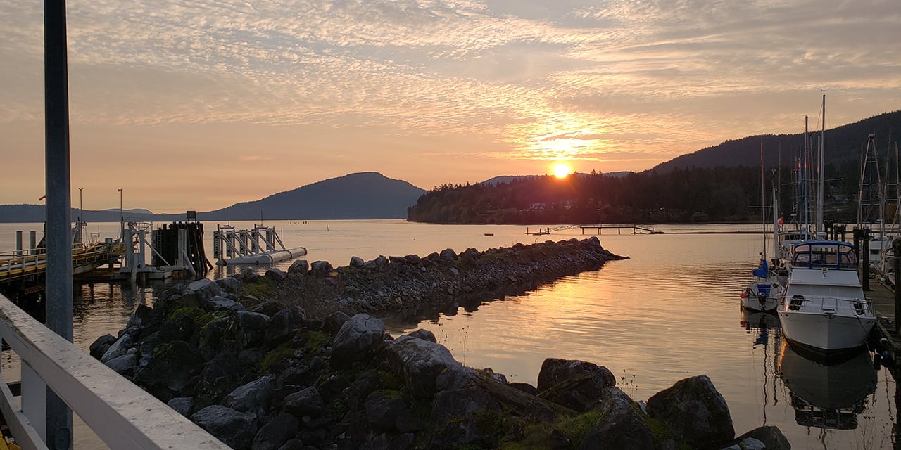 View off a Vancouver Island ferry, with a sun rising in the background and boats in the harbour