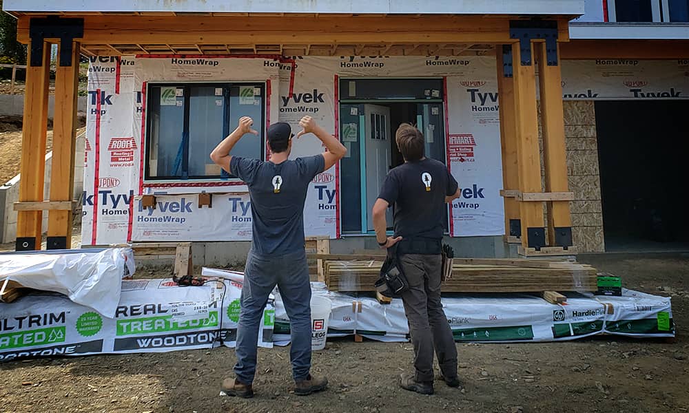 Electrician Jaro Bixby standing with a co-worker outside a residential home being built