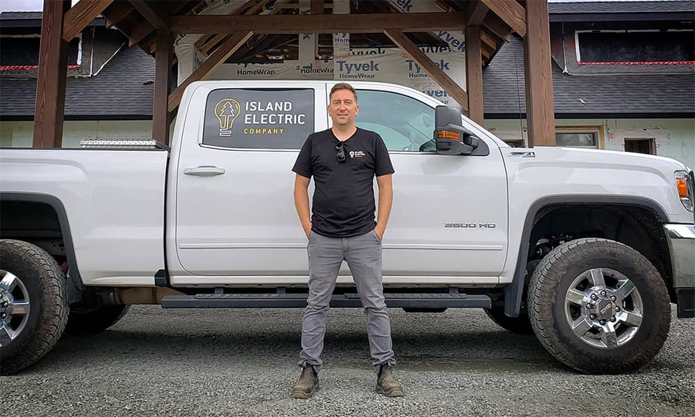 Shawn Lamoureux, standing in front of a white pickup truck with the Island Electric Company logo on the rear tinted window